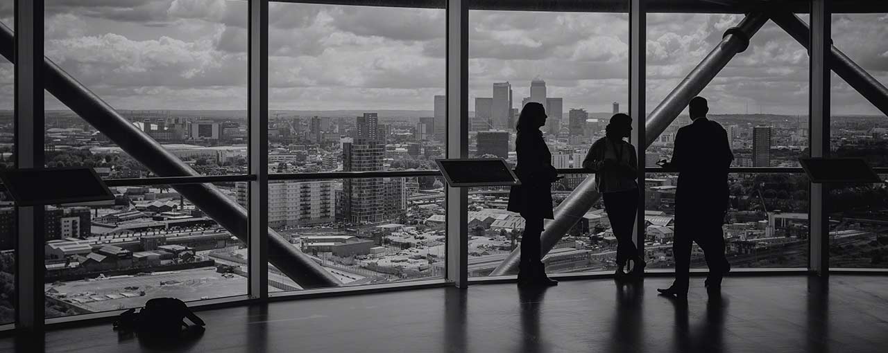 3 personnes discutant dans un bâtiment d'entreprise avec vue sur la ville.