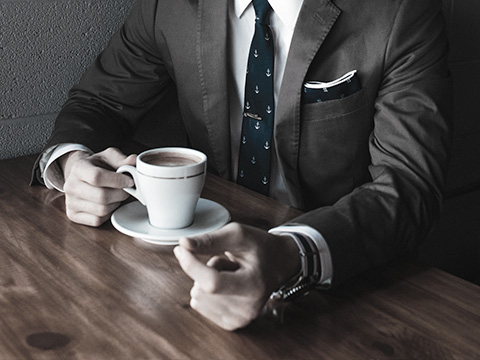 Prestation destinée pour les professionnels, homme en costume face à sa tasse de café.